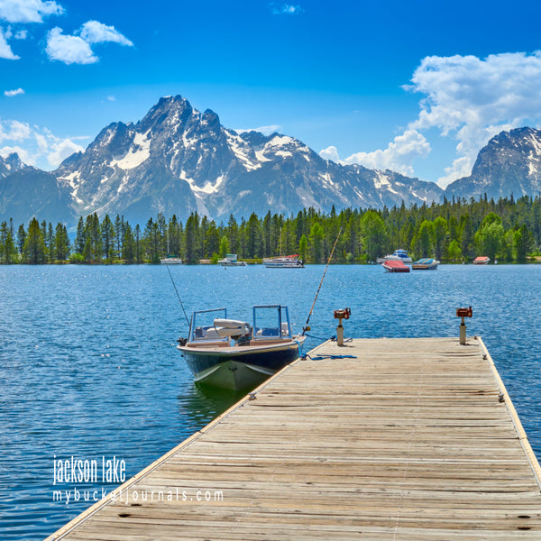 wooden dock jutting out on a lake with mountains in the background