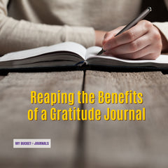 the hands of a woman with the pen sitting at a wooden table writing in a journal