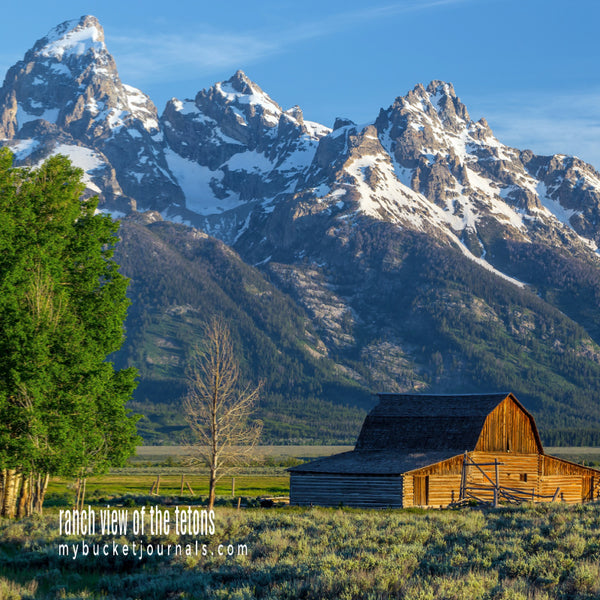old barn sitting on green acreage with mountains in the background