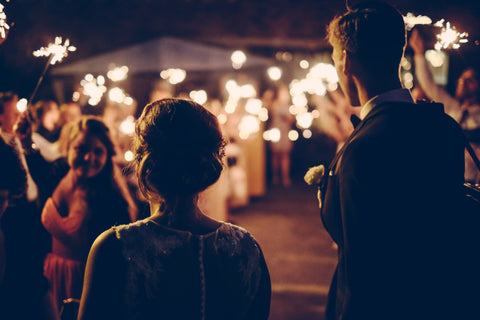 married couple waiting to make their wedding grand exit through a sparkler tunnel made by guests