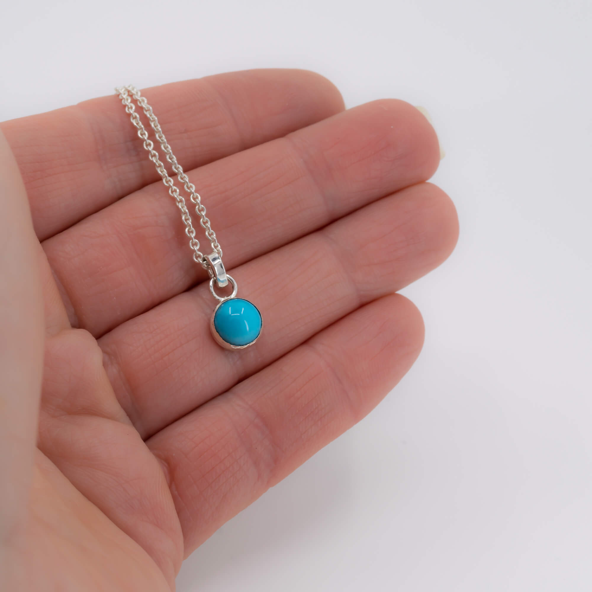 Dainty Round Sleeping beauty turquoise minimalist sterling silver pendant necklace shown in hand for scale