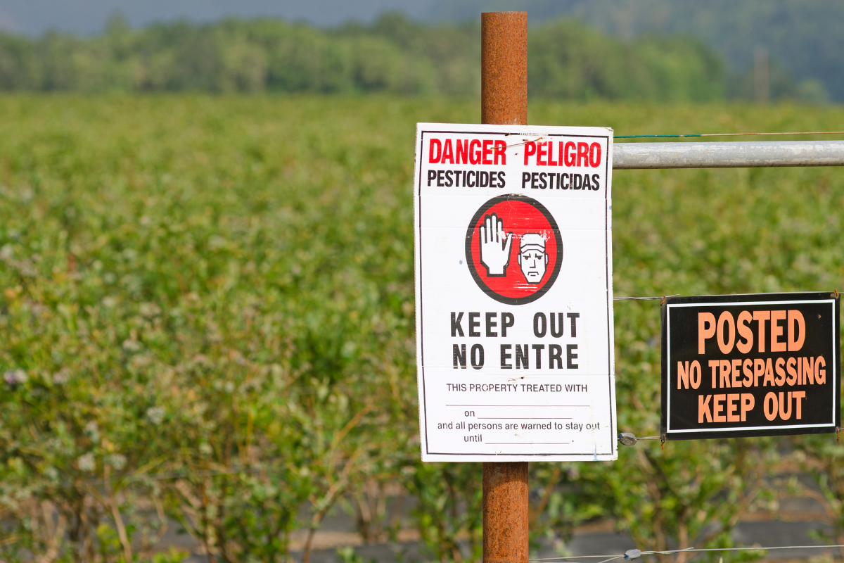 a danger pesticide keep out sign in front of a field of crops
