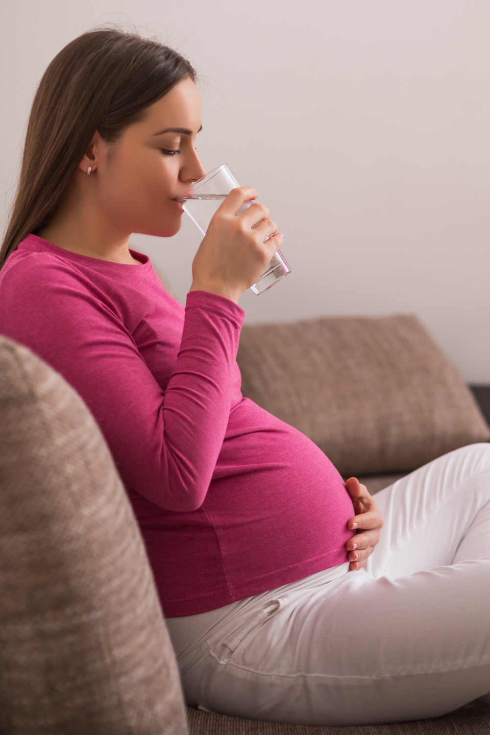 pregnant woman drinking water at home