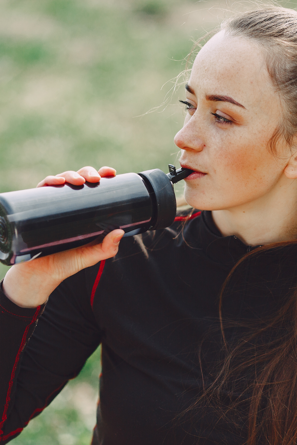 woman drinking from plastic reusable water bottle