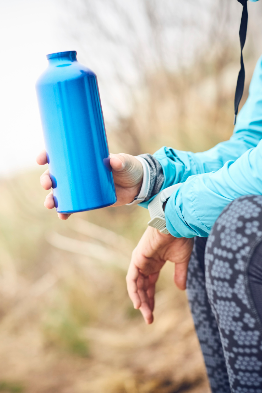 person outdoors holding a blue water bottle