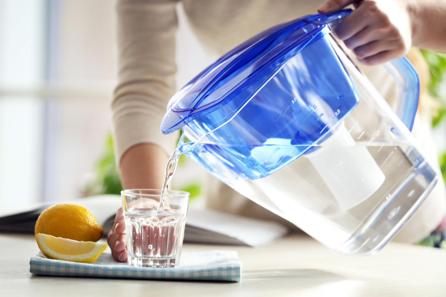 woman pouring water into glass from water filter