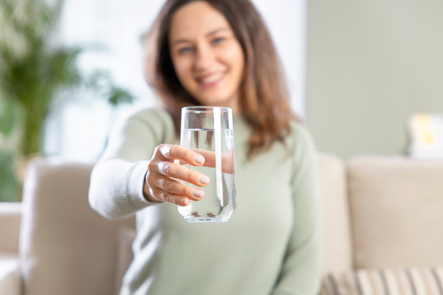 woman holding up glass of purified and filtered water