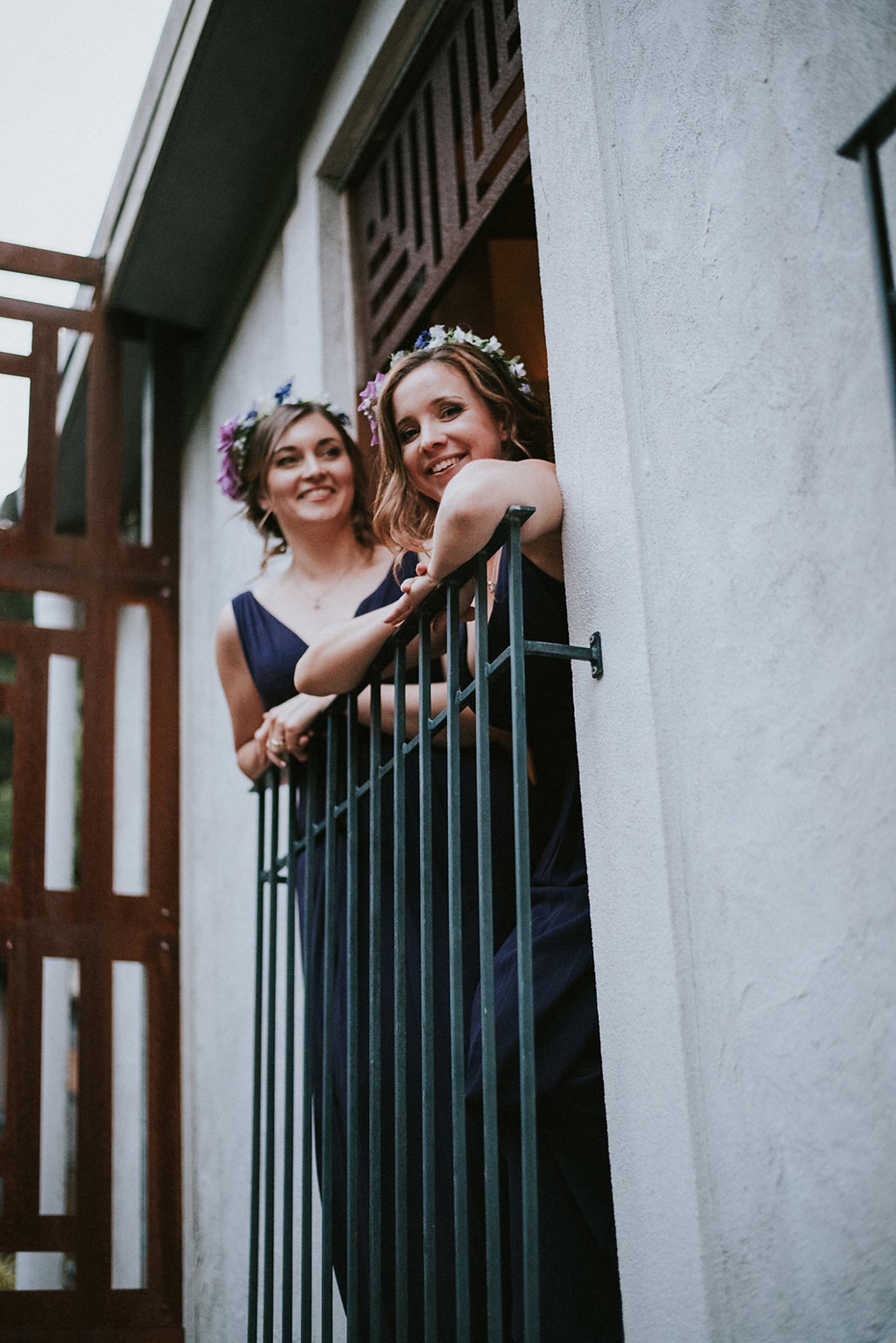 bridesmaids in purple dresses looking over balcony at wedding venue