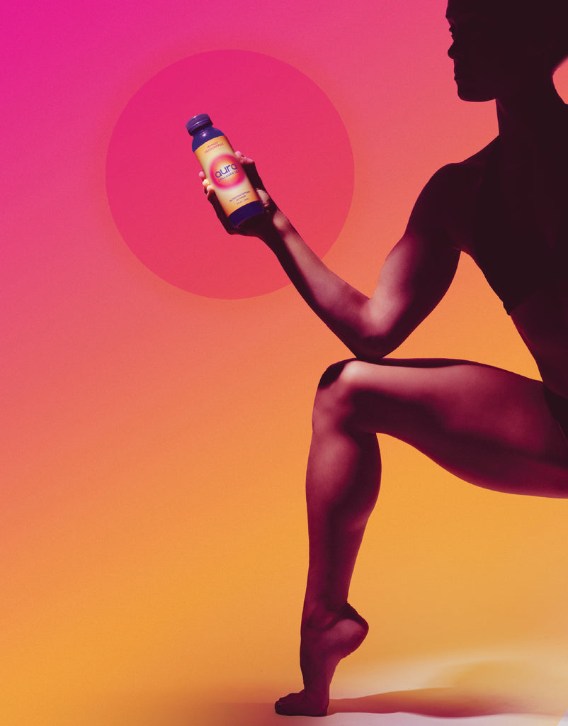 Person posing with AURA bottle against gradient background