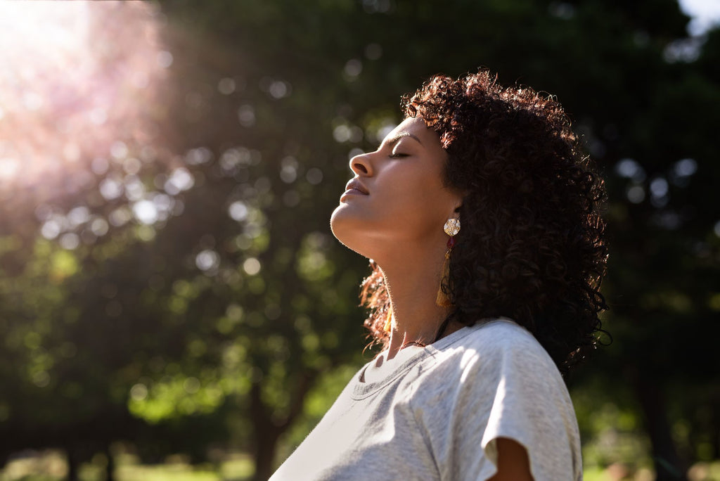 Woman meditating with eyes closed sitting in the sun