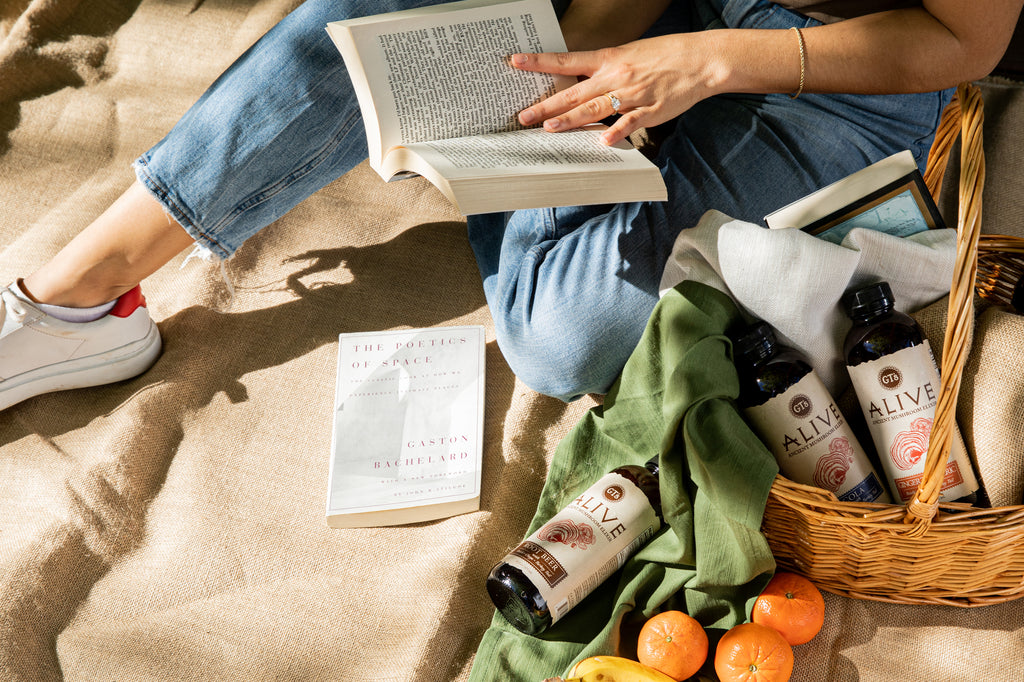 Woman reading a book with GT's ALIVE Ancient Mushroom Elixir