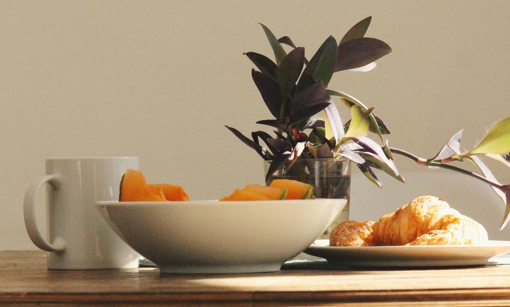 Closeup of fruit in bowl with cup and croissant