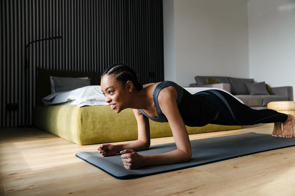 Woman exercising in bedroom doing ab plank