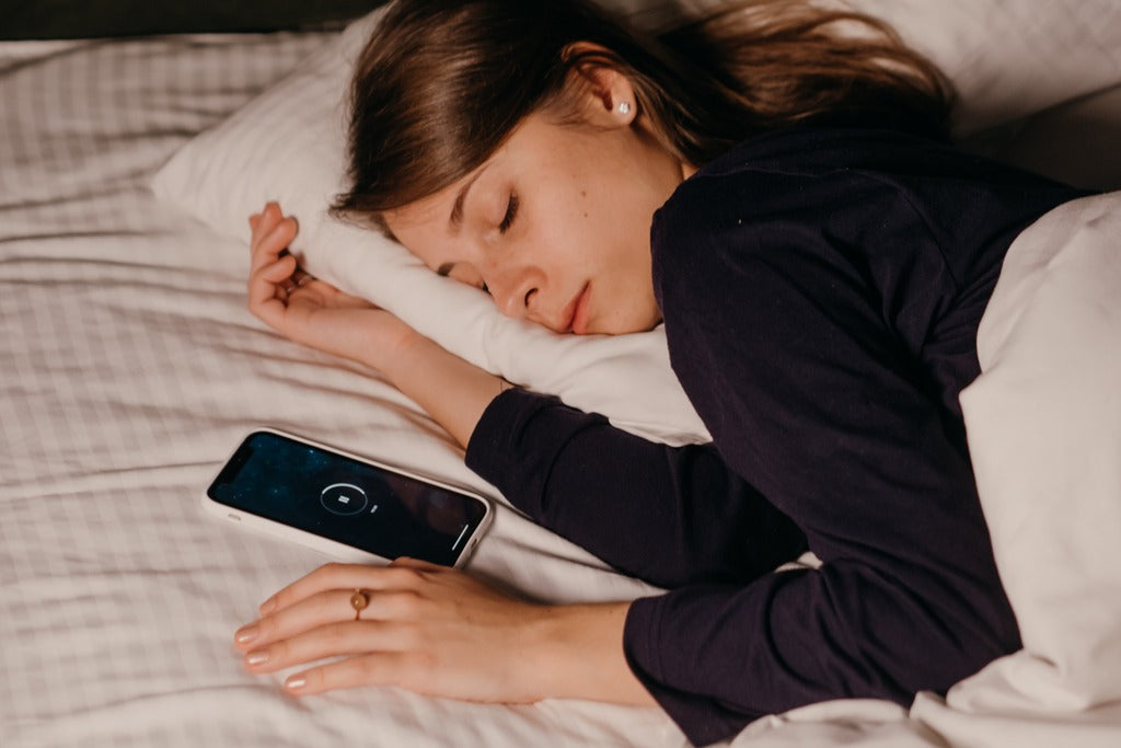 Woman sleeping on bed next to phone