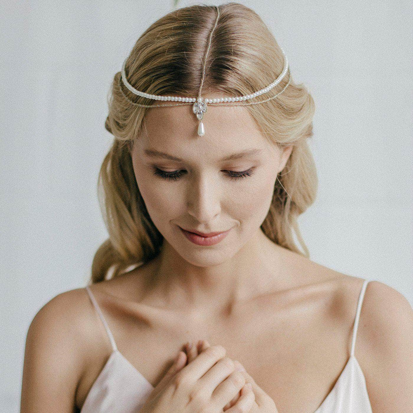 strings of beads and pearls draped over the head of a blonde white woman. All tied to a central crystal piece