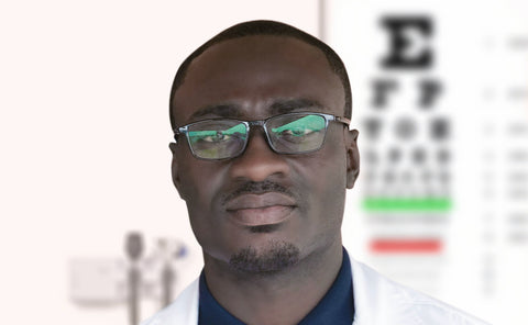 Eye doctor standing in front of a blurred eye chart in the background. Be sure to get regular check-ups to catch Age-Related Macular Degeneration Early!