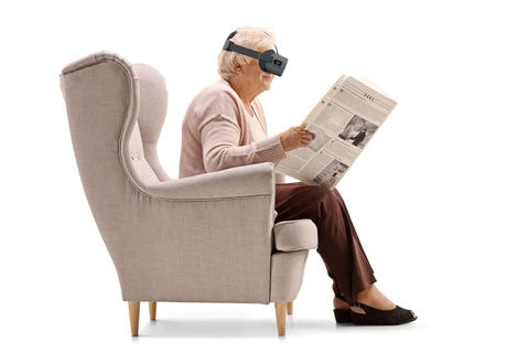 Elderly woman sitting on couch and reading newspaper with Vision Buddy