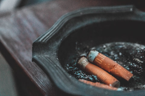 Smoking can increase your risk for macular degeneration. Picture of two cigarettes in a dark ashtray.