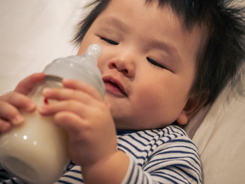 Baby looks at milk bottle