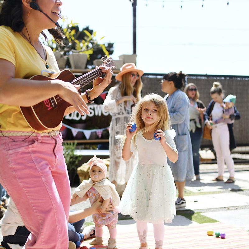 Photo - Woman dancing while playing ukulele for children