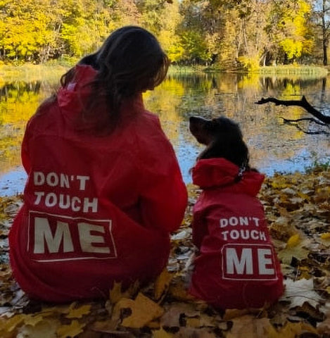 Human and dog in a red Menace™ - Matching Dog & Owner Raincoat, Medium and Large Dogs on a vivid background.