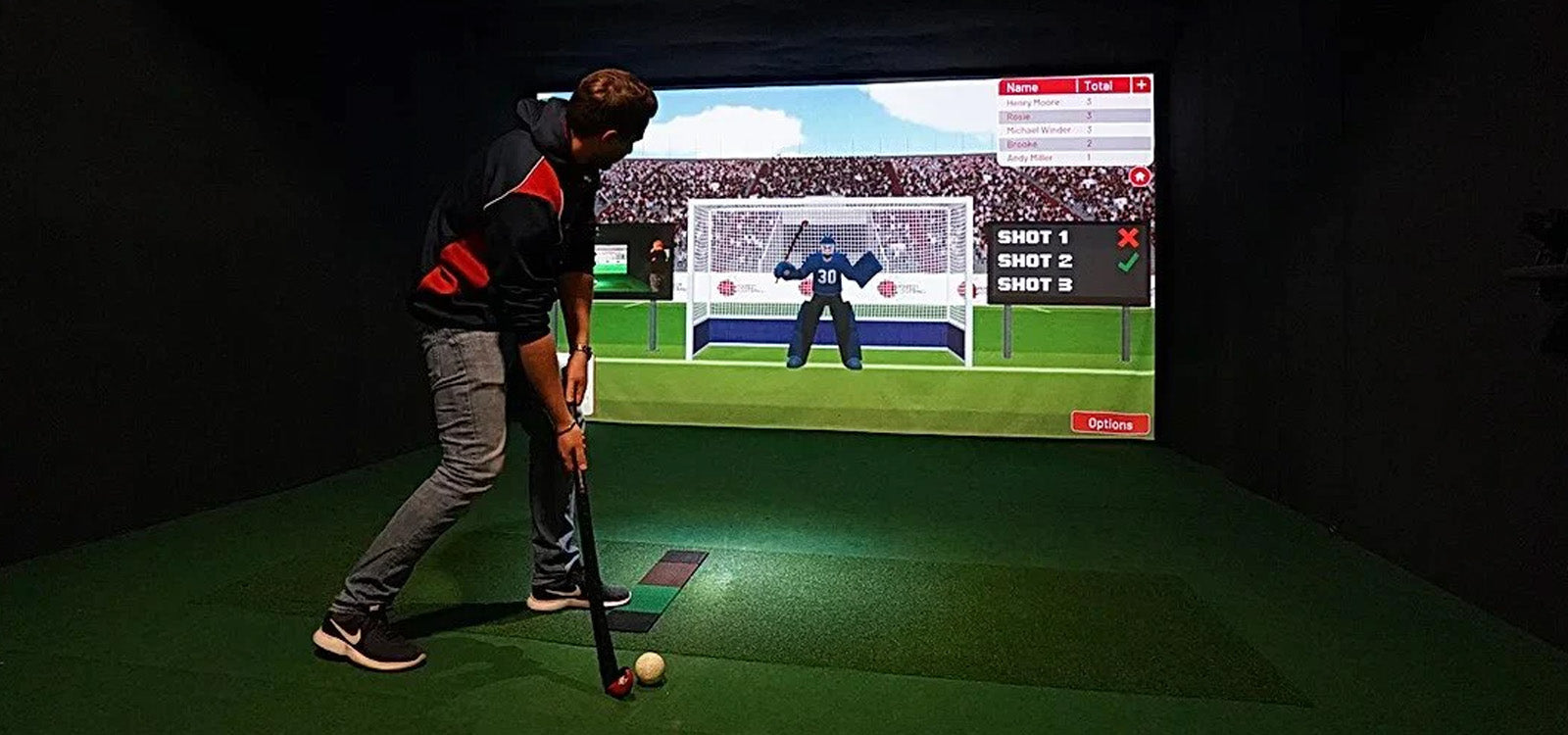 Man swinging field hockey stick at ball in Sports Coach simulator