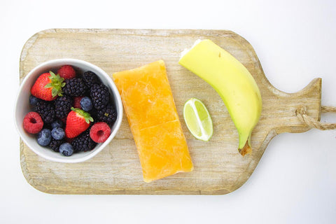 Acerola package with mixed berries and banana on cutting board