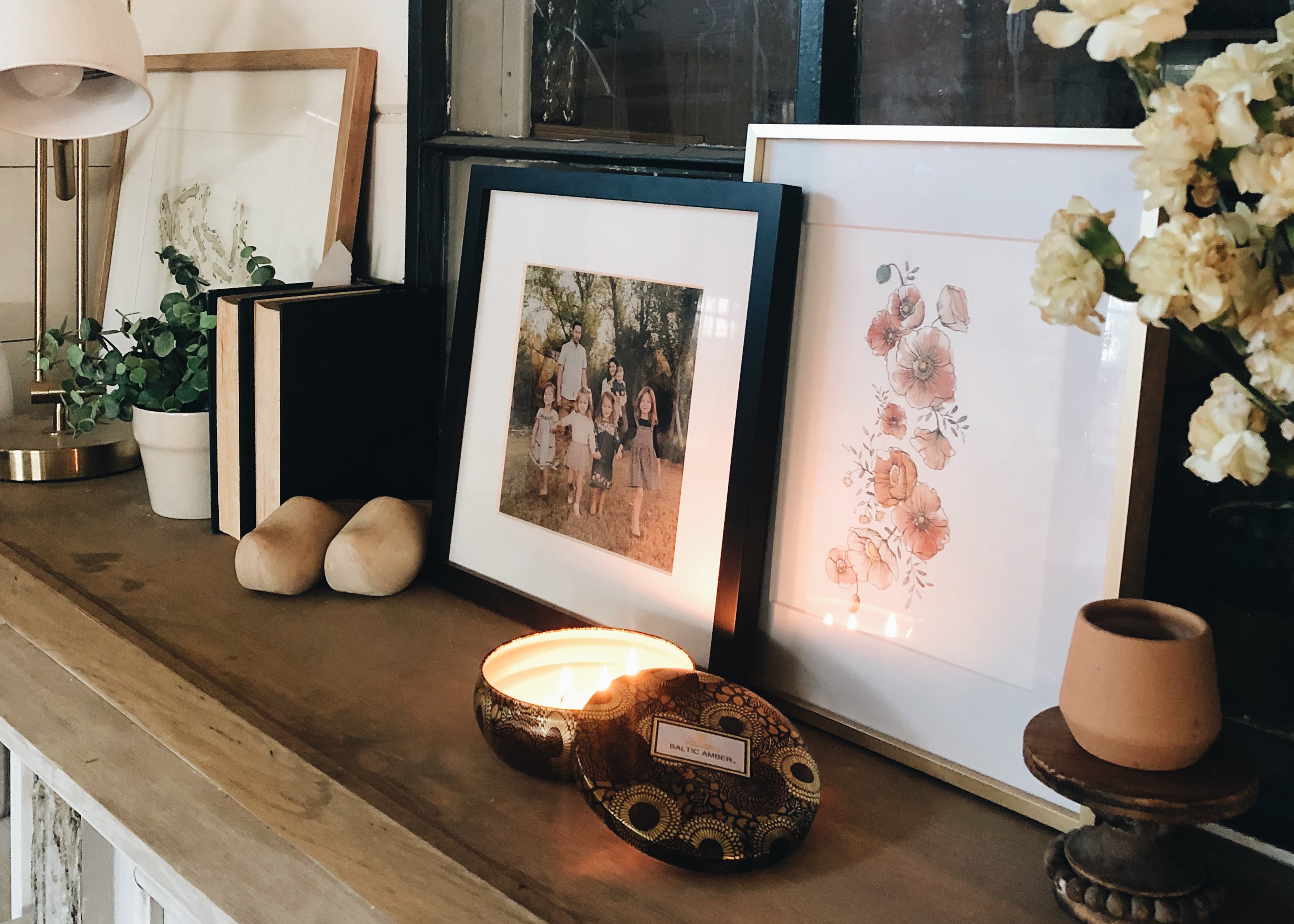 fireplace mantle with candles and florals paintings
