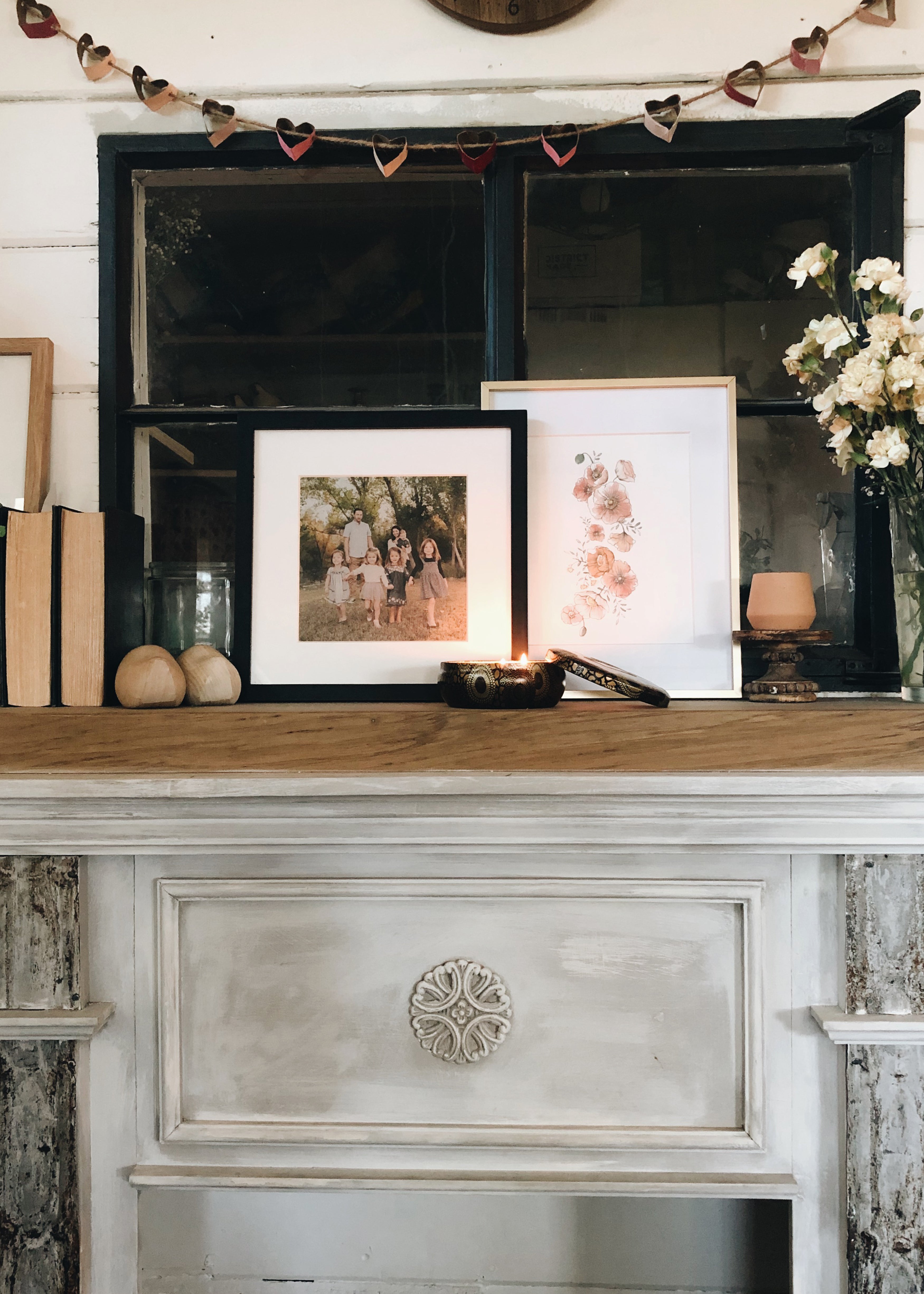 mantle with candles and family photo and framed painting of flowers