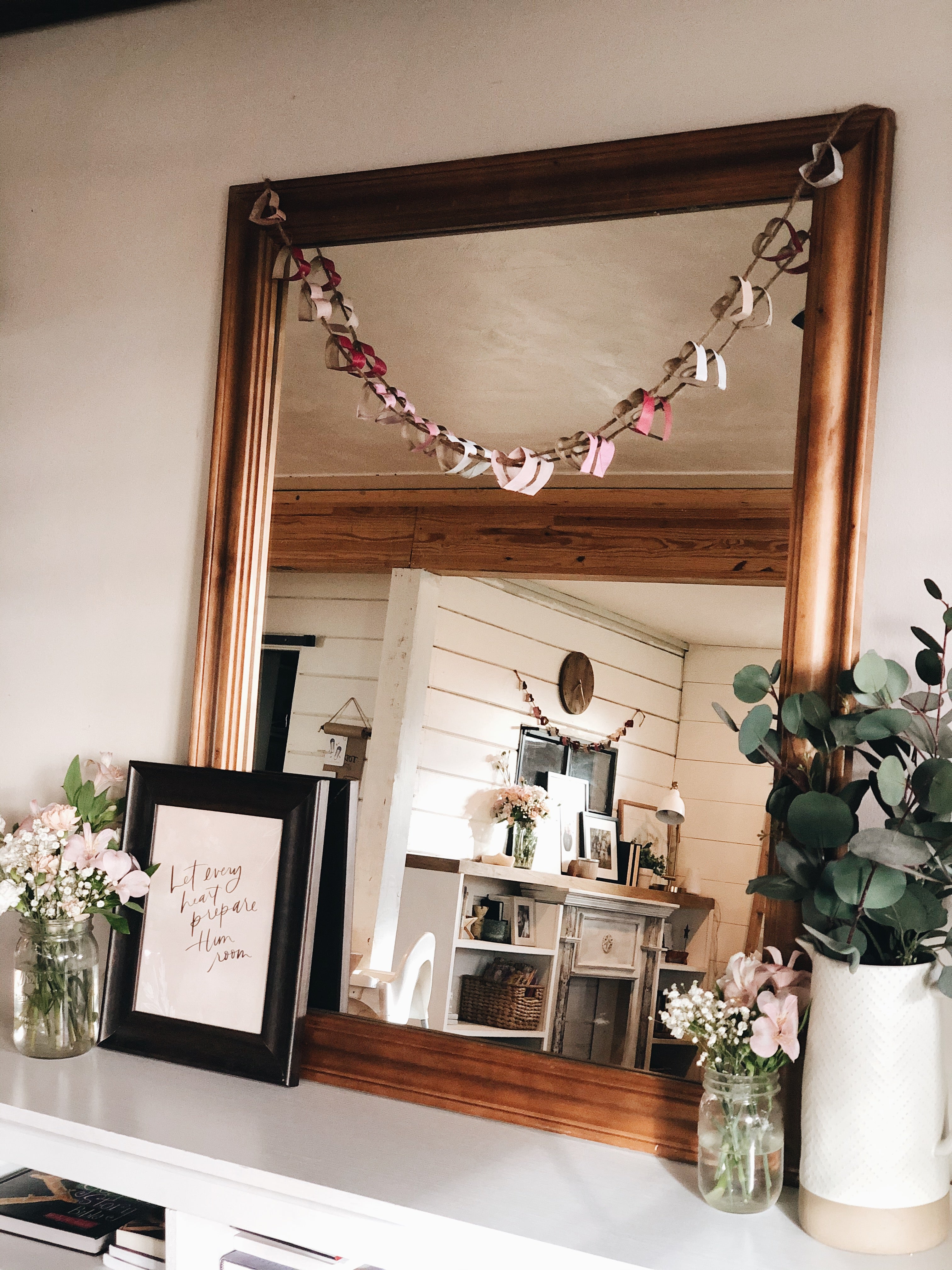 pink and red painted heart garland hanging on a mirror in living room