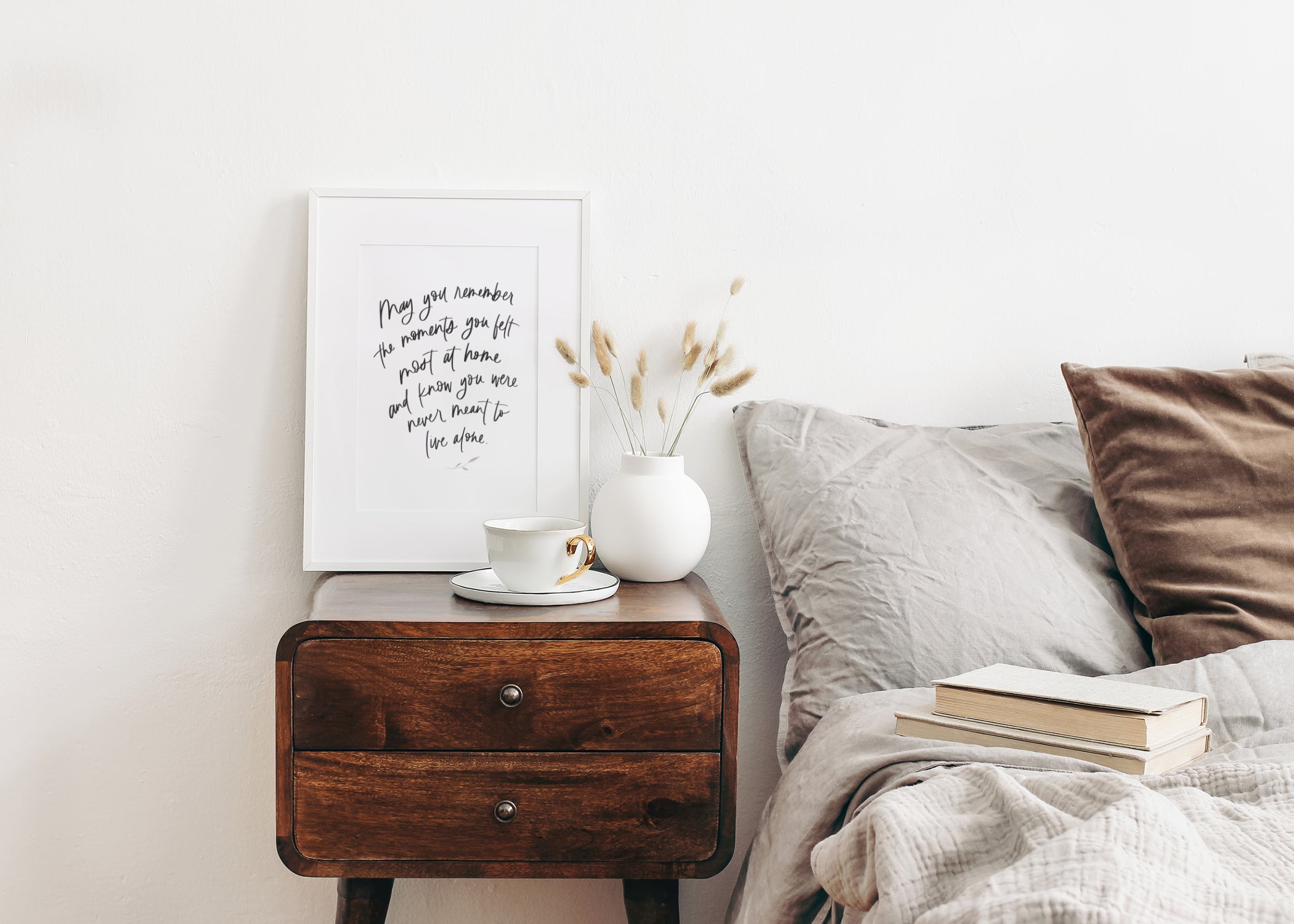 framed hand lettered artwork on nightstand next to a bed in bedroom