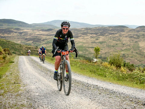 woman in Reilly kit rides on gravel path