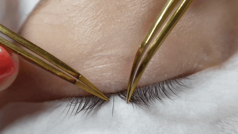 Isolating individual lashes with lash tweezers for lash extensions