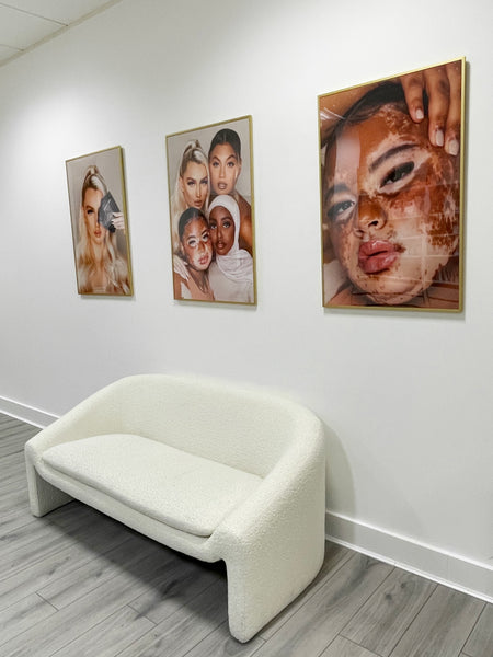 a salon reception area with a small sofa and three lash posters