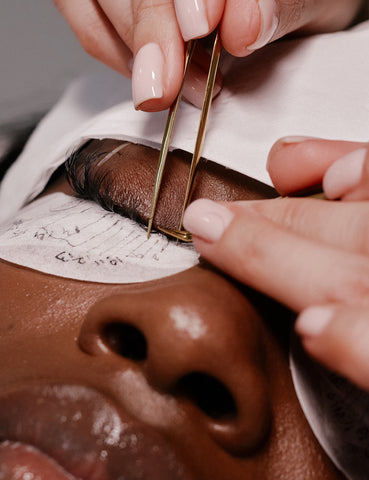 Lash Technician isolating individual lashes with eyelash tweezers to apply eyelash extensions