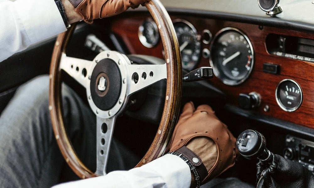 Gants de conduite en cuir marron roasted dans voiture de collection vintage.