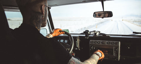 Homme avec gants de conduite en cuir au volant.