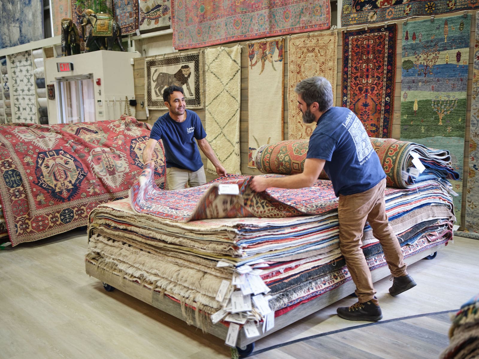 Landry and Arcari rug specialists flipping through rug piles in the showroom