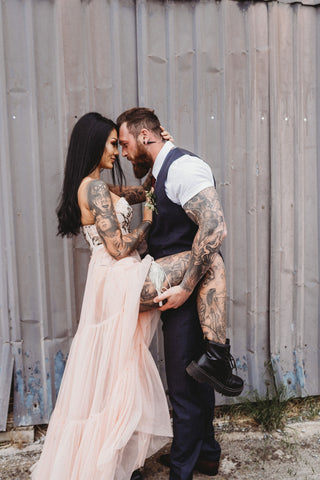 Image shows Tattooed Couple in pink wedding down wearing Hayze Bridal Zinnia Garter