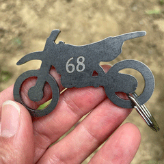 Hand holding dirt bike metal keychain engraved with number 68