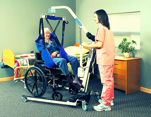 Patient lift and sling are being used by an elderly and a caregiver nurse in homecare setting 