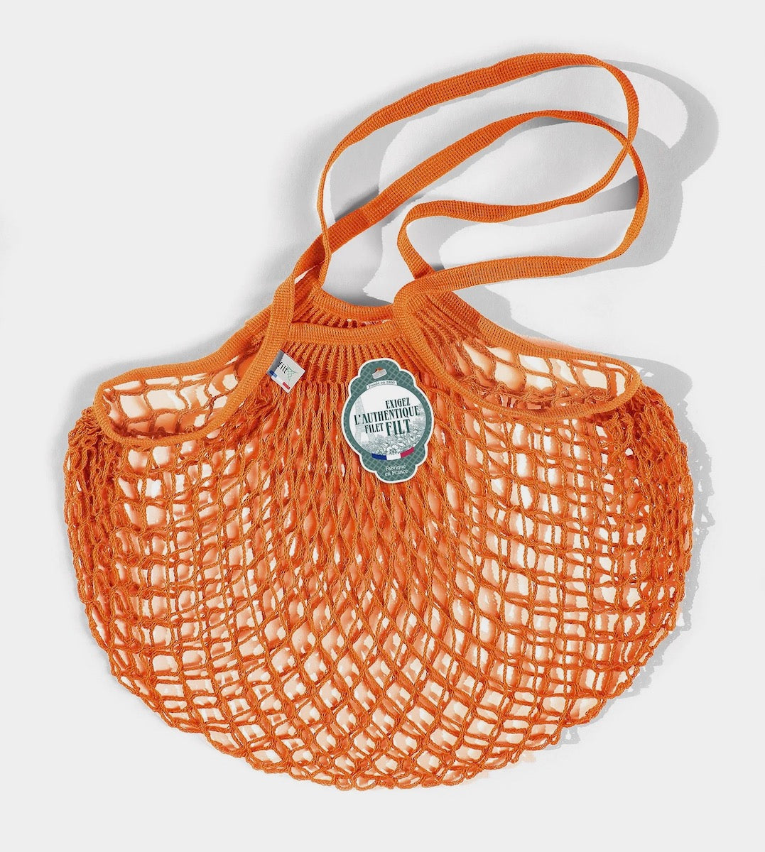 Orange net market bag sits on a white background