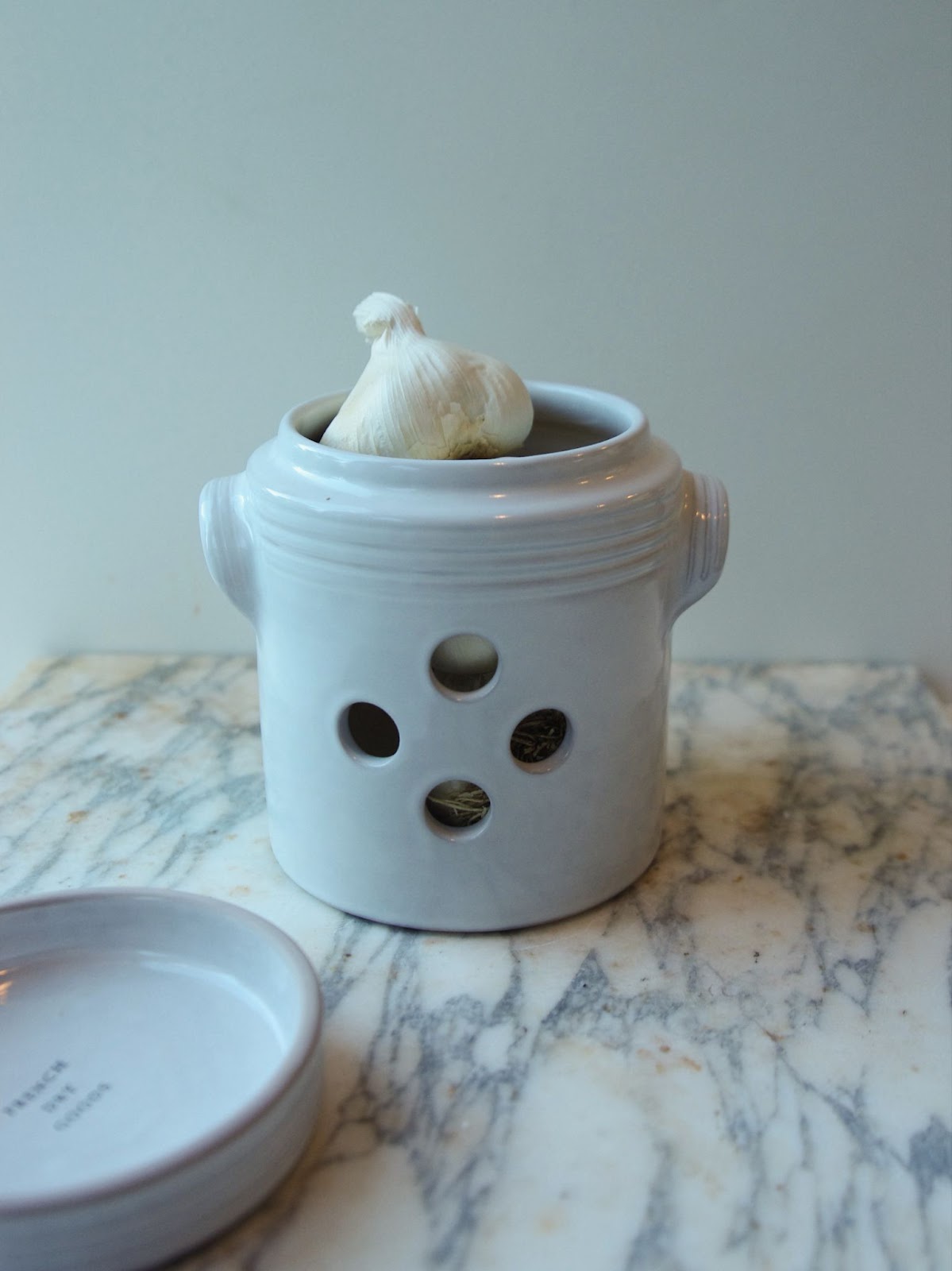 Garlic pot with lid, handles, and four holes in the front.