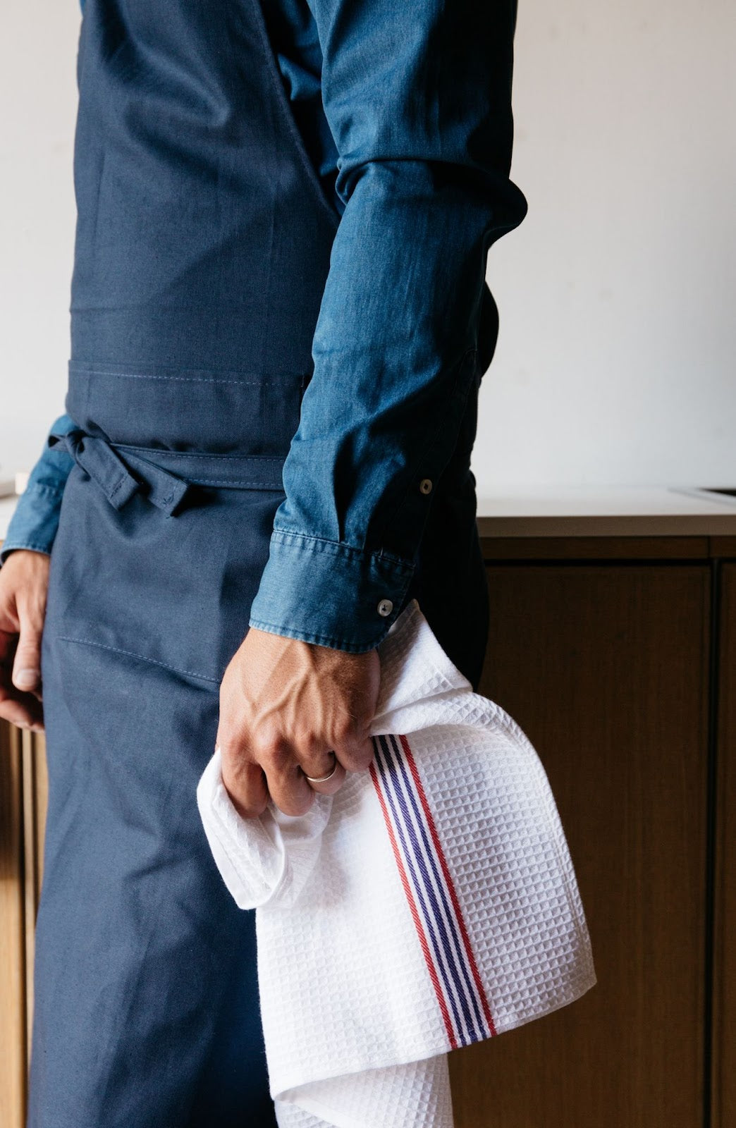 Person with apron holding honeycomb textured dish towel with red, white and blue stripes.