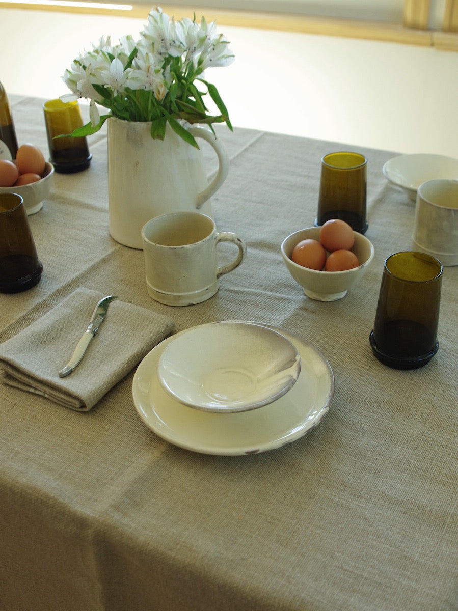 Thieffry linen table cloth on table with Avoine et Terre oat colored dinnerware on top with flowers