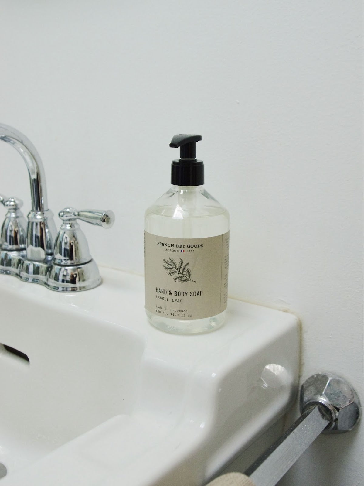 Laurel leaf scented liquid hand and body soap bottle with pump on bathroom sink.