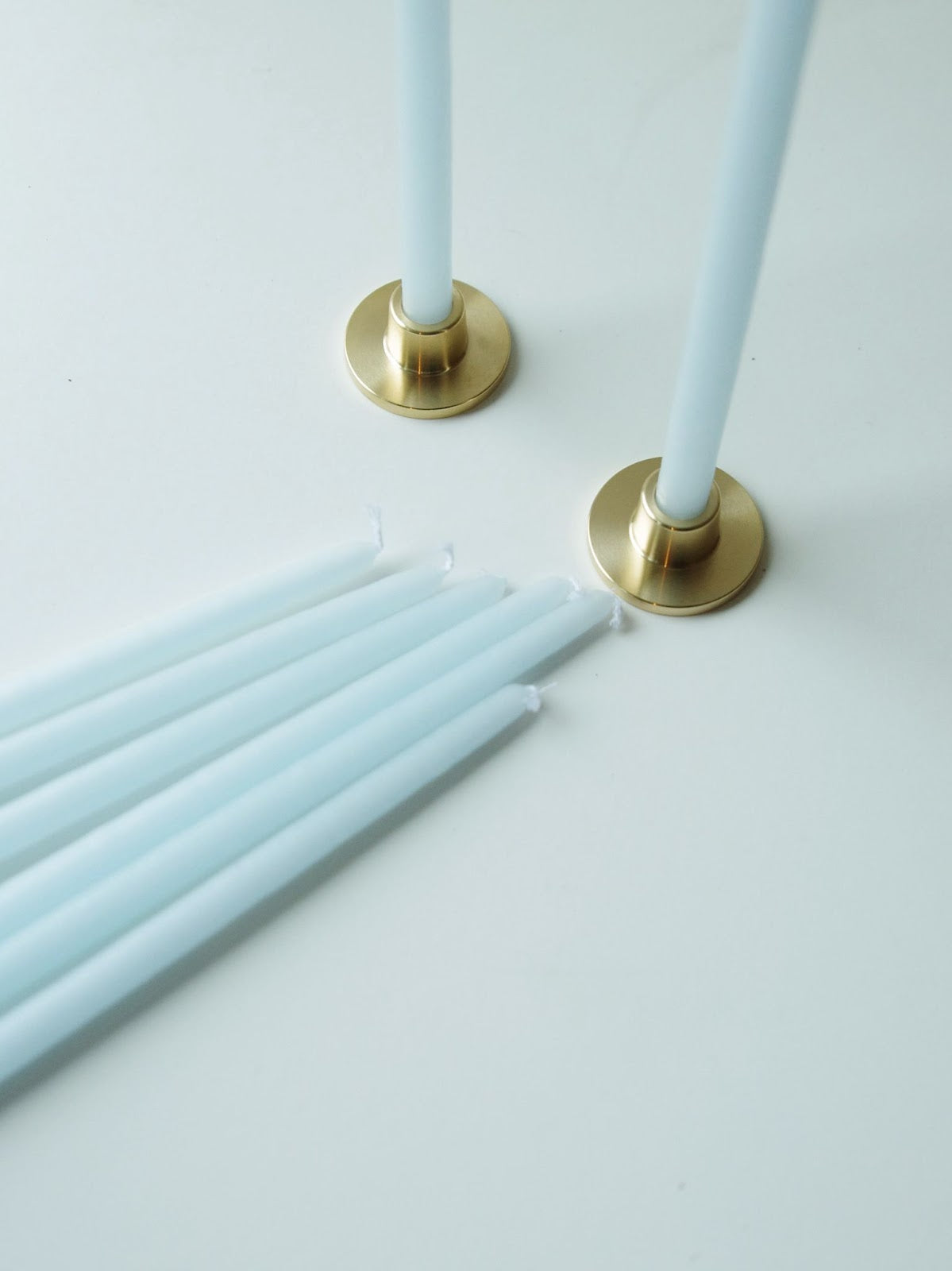 Light blue long taper candles and minimal brass holders.