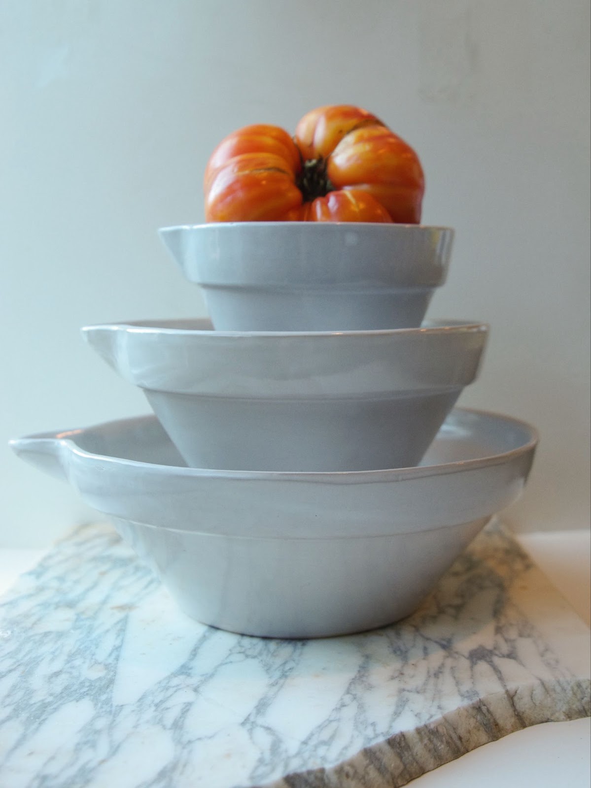 Stack of three white mixing bowls with pour spouts, in small, medium, and large.