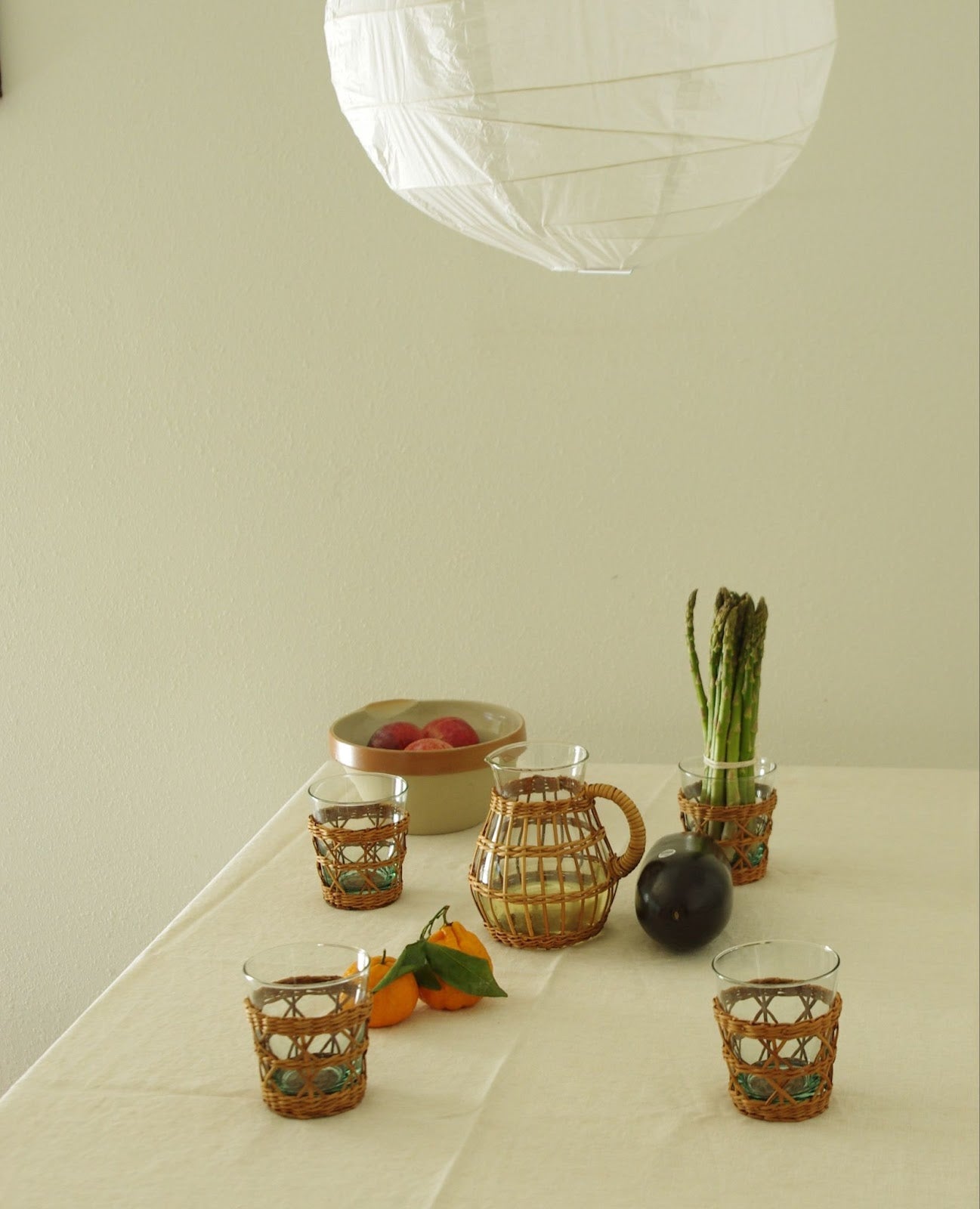 Rattan wrapped glassware on table under paper lantern.