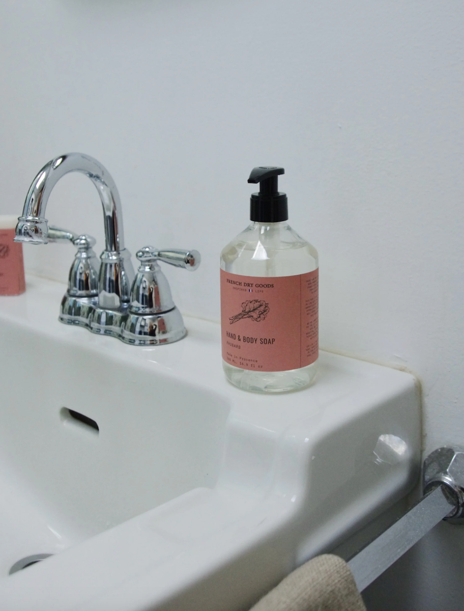 Rhubarb hand pump soap sits on the edge of a white bathroom sink.